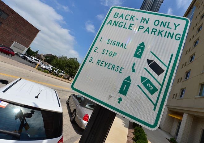 Signs on Southwest Monroe Street explain the new reverse-angle parking spots from Main to Fulton. Reverse-angle parking requires drivers to back into their spots, but is supposed to increase visibility of oncoming traffic when exiting.