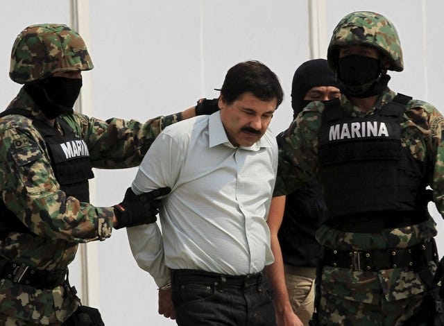 Joaquin "El Chapo" Guzman, center, is escorted by soldiers during a presentation at the Navy's airstrip in Mexico City in this February 22, 2014 file photo. Guzman, Mexico's most notorious drug lord, escaped from his high security prison in central Mexico, the country's national security commission said on Sunday, July 12, 2015. (REUTERS/Henry Romero/Files)