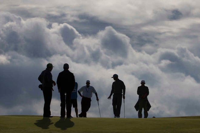 Tiger Woods, second from right, walks across the 11th green during a practice round Monday at St Andrews Golf Club prior to the start of the British Open in St. Andrews, Scotland. (AP Photo/Jon Super)