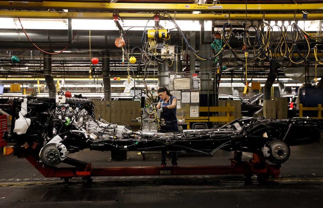 An employee works on the assembly line at the General Motors plant in Arlington, Texas, Tuesday July 14, 2015. General Motors plans to spend $1.4 billion to expand and improve the SUV producing plant to meet strong demand for its vehicles. (AP Photo/Tony Gutierrez)