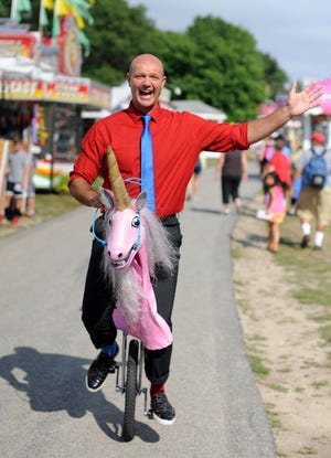 Guy Collins, "the Groovy Guy," of Warren, Vt. rides Rusty the Unicorn during the Barnstable County Fair opening day at Cape Cod Fairgrounds.