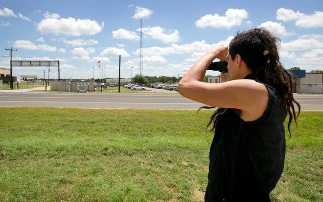 Derrick Broze, left, an activist/journalist from Houston, keeps watch on the entrance to Camp Swift in Bastrop, Texas, on the first day of the Operation Jade Helm 15 military exercise on Wednesday July 15, 2015.  Jade Helm 15 is summer military training exercise that has aroused alarm among archconservative Texans. (Jay Janner/Austin American-Statesman via AP) AUSTIN CHRONICLE OUT, COMMUNITY IMPACT OUT, INTERNET AND TV MUST CREDIT PHOTOGRAPHER AND STATESMAN.COM, MAGS OUT; MANDATORY CREDIT