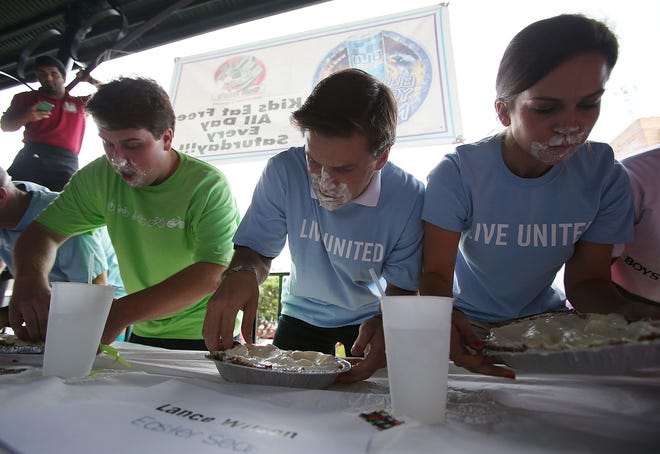 Contestants pick up the key lime pies and begin using their hands after 30-seconds with hands behind their backs during the second annual pie-eating contest held by the United Way of West Alabama at Don Tonio's Mexican Restaurant in Temerson Square in downtown Tuscaloosa, Ala. on Thursday July 16, 2015.