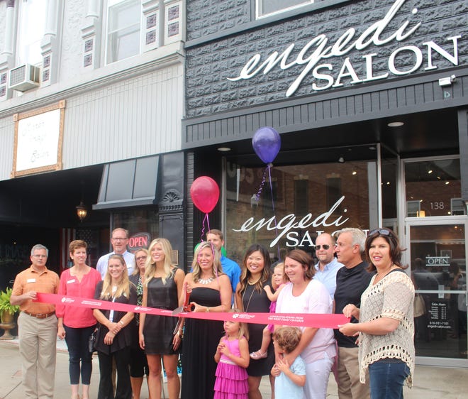 A group of employees, family and friends gather around Jenny Hoort, owner of Engedi Salon, as she prepares to cut the ribbon at the grand opening of a downtown Zeeland location on Friday, July 17. Justine McGuire/Sentinel staff