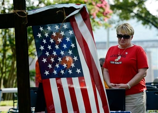 Dianna Varnes stands by a table adorned with photographs of the Marines who died after a memorial service at River Park Saturday, July 18, 2015, in Chattanooga, Tenn. The U.S. Navy says a sailor who was shot in the attack on a military facility in Chattanooga has died, raising the death toll to five people. Muhammad Youssef Abdulazeez, of Hixson, Tenn., attacked two military facilities on Thursday, in a shooting rampage that killed four Marines and one U.S. Navy sailor. (AP Photo/Mark Zaleski)