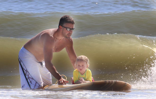 Joey Kromash, 2, gets help from his dad, Jason, to master a surfboard at this year's Pipeline to a Cure, a surfing event that teaches people with Cystic Fibrosis in New Smyrna Beach. Get your beach time in early Sunday, as storms forecast for the afternoon in Volusia and Flagler counties. News-Journal/JIM TILLER