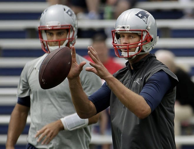 Patriots quarterback Tom Brady takes a snap as backup quarterback Jimmy Garoppolo looks on during minicamp practice in Foxboro.