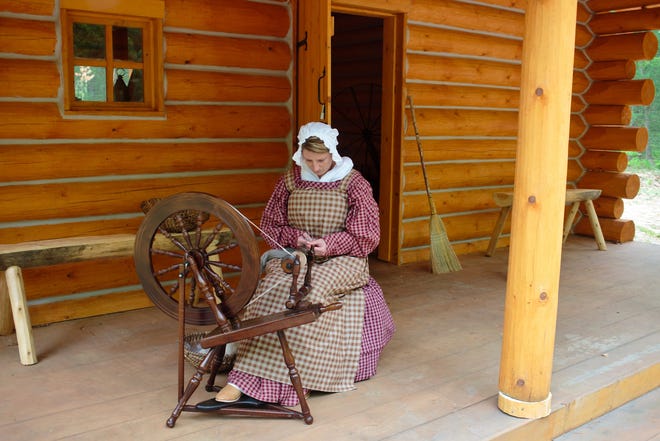 Melissa Horton spins yarn on the front porch of an 1830's settlers cabin at Michigan's Heritage Park in Whitehall, Mich. The park at Hilt's Landing is operated by the Lakeshore Museum Center and will be open from June 6 through October. AP