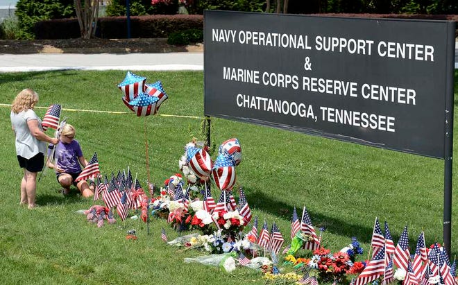 Kelly Caparell, left, and her daughter Keldon Bevel, place several American flags by a makeshift memorial at the entrance to the Naval Operational Support Center and Marine Reserve Center Saturday, July 18, 2015, in Chattanooga, Tenn. The U.S. Navy says a sailor who was shot in the attack on a military facility in Chattanooga has died, raising the death toll to five people. (AP Photo/Mark Zaleski)
