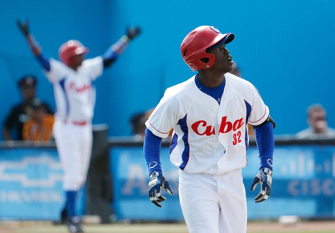 Cuba's Jose Garcia watches his ball while hitting a walk off home run off Puerto Rico pitcher Raul Rivera in the ninth inning of the bronze medal baseball game at the Pan Am Games, Sunday, July 19, 2015, in Ajax, Ontario. Cuba won 7-6.