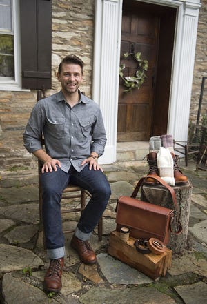 Lucas Darway, founder of Arcane Supply Co., a brands initiative hoping to bring the production of U.S.-made men's goods back to the region, poses with his goods in Feasterville on Wednesday, July 8, 2015. Darway' makes everything in the photo except for the boots, which are Original Chippewa, but he does still sell them as a third-party item. The wool socks are 100% alpaca wool boot socks, he also sells leather belts, messanger bags, 'boot balm,' and the shirt and jeans he is wearing. His leather goods are custom and made to order. He is on instagram at @arcanesupplyco, and on the web at http://arcanesupply.com/.