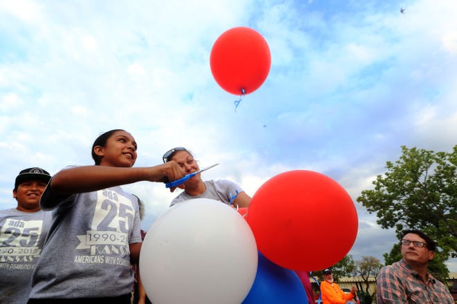 Elena Rivera, 11, cuts a balloon free as her mother holds a group of balloons and her brother Xavier, 10, left, looks on during the 25th Anniversary of the Americans with Disabilities Act celebration Tuesday, July 21, 2015 at George Pyle Park. 25 balloons were released in celebration of the 25th anniversary of the ADA being signed into law.