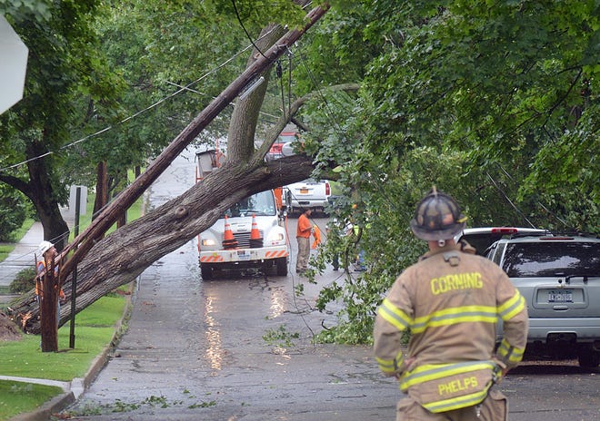 A Corning City firefighter checks out the scene on Watauga Avenue in Corning Tuesday afternoon where a large maple tree was knocked over during a thunderstorm taking a telephone pole and power lines with it.