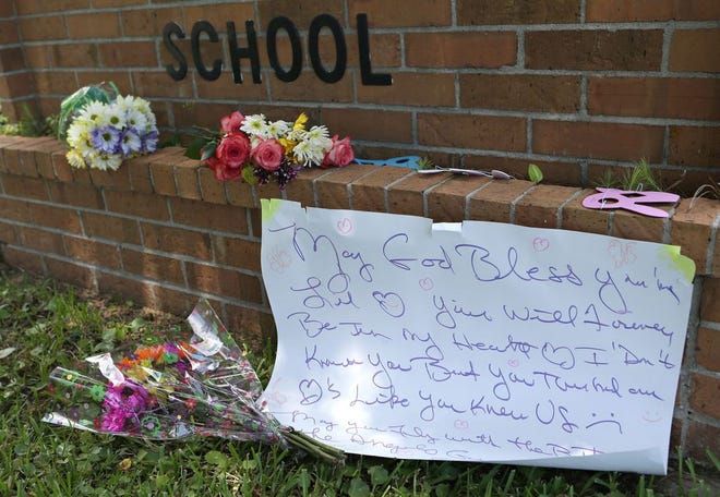 Flowers and notes of sympathy adorn the sign at Cedar Grove Elementary School after a tragic accident Tuesday killed the 18-month-old daughter of a teacher after the toddler was left most of the day inside a hot car in the parking lot on Wednesday, June 3, 2015, in Panama City, Fla. (Heather Leiphart | The News Herald)