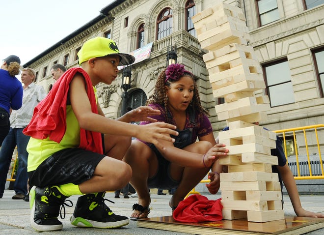 Kolby, 10, and Nadia Jones, 11, who are visiting from New York, watch the tower fall during a giant game of Jenga during the Worcester Local Weekend celebration on the Worcester Common.T&G Staff/Christine Hochkeppel
