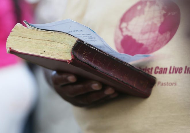 A person outside of Plum Grove Baptist Church holds a bible.