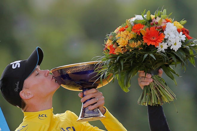 Overall winner Chris Froome kisses the trophy as he stands on the podium at the end of the Tour de France on Sunday. The Associated Press