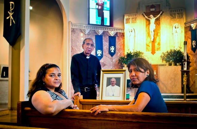 In this Friday, July 24, 2015 photo, Maria Rodriguez, left, Father Diego Villegas, center, and Alma Reyes pose with a photo of Pope Francis at Queen's Saint Leo's church, in New York. They are part of a team organizing a workshop at the church to talk about the pope's teachings in advance of his U.S. trip. (AP Photo/Bebeto Matthews)