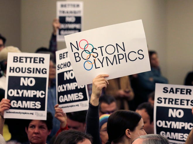 In this Feb. 5, 2015, file photo, people hold up placards against the Olympic Games coming to Boston, during the first public forum regarding the city's 2024 Olympic bid, in Boston. Boston's mayor delivered a harsh blow to the city's effort to host the 2024 Olympics on Monday, July 27, 2015, when he declared he wouldn't sign any document "that puts one dollar of taxpayer money on the line for one penny of overruns on the Olympics." Now Los Angeles may be the best bet for a U.S. bid.