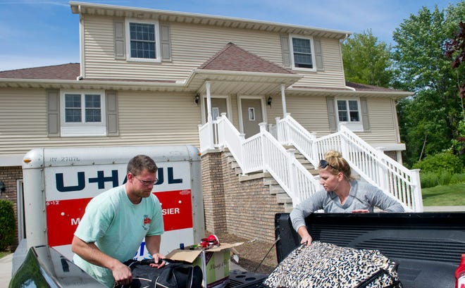 Jim Benke, 26, left, unloads luggage with his girlfriend Chandler Smith, 25, as they move into their Glen Eagles rental townhome on July 22 in Millcreek Township. The couple moved from Perry Hall, Md. for Benke to attend medical school at LECOM. ANDY COLWELL/