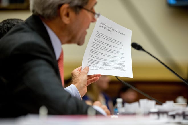 Secretary of State John Kerry holds up an article as he testifies on Capitol Hill in Washington, Tuesday, July 28, 2015, before the House Foreign Affairs Committee hearing on the Iran Nuclear Agreement. Kerry pitched the administration's controversial nuclear deal with Iran before a skeptical House Foreign Affairs Committee on Tuesday, pushing back against the allegation it would ease crippling sanctions forever in exchange for temporary concessions on weapons development. (AP Photo/Andrew Harnik)