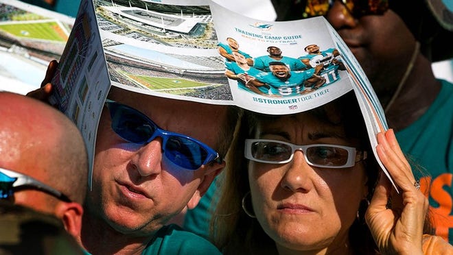 Jim and Suzanne Dunn, Pompano Beach, shade themselves as the watch their first Dolphins training camp in Davie, Florida on July 25, 2014. (Allen Eyestone / The Palm Beach Post)