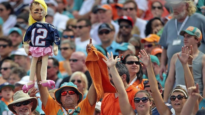 Miami Dolphins fans hold up a doll with a picture of Tom Brady’s on it Sept. 07, 2014 in Miami Gardens. (Bill Ingram / Palm Beach Post)