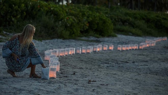 Lilly Folds, Jupiter, lights paper lanterns as hundreds gathered at Jupiter Inlet Park for a candlelight vigil and paper balloon release and offer prayers for missing Tequesta teenagers Austin Stephanos and Perry Cohen on Monday, July 27, 2015. The boys capsized boat has been recovered after they went fishing on July 24. (Thomas Cordy / The Palm Beach Post)