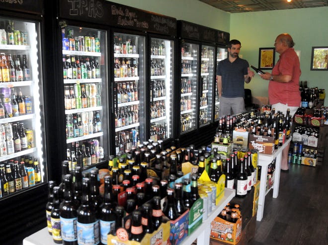 Hey!Beer owner Mike Duffy (left) talks with a customer in his S. Kerr Ave. bottle shop. STARNEWS FILE PHOTO