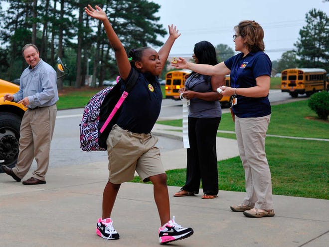 A student celebrates while walking off a bus during the first day of school at Oglethorpe Avenue Elementary on Monday, August 11, 2014, in Athens, Georgia. (AJ Reynolds/Staff, @ajreynoldsphoto)