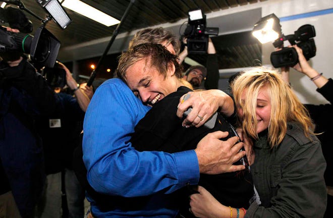 Derrik Sweeney, center, hugs his father Kevin Sweeney, left, and sister Ashley, right, Derrik arrived at Lambert-St. Louis International Airport in St. Louis.  Sweeney and two other American students were arrested on the roof of a university building near Tahrir Square in Cairo accused of throwing firebombs at security forces fighting with protesters. Scholars and students across the U.S., are attracted to international hotspots as subjects of study, experts say, and as an opportunity to see historic events unfold from a front-row seat however, it's a challenge for colleges and universities to weigh the benefits against safety risks and they often refuse to sponsor travel to areas in conflict. (AP Photo/Jeff Roberson, File)