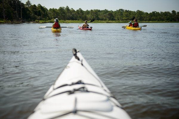 The Coley family paddles down the lower Cape Fear River in kayaks at Carolina Beach State Park.