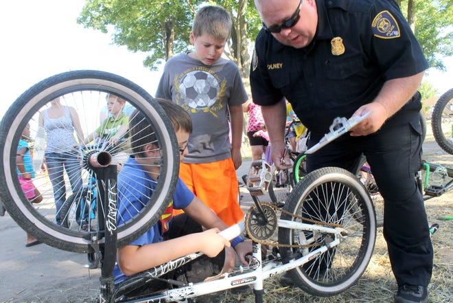 Quincy Police Chief Scot Olney helps Ethan Trennezahl, 10, and his brother, Jacob, 8, register their bicycles. ANDY BARRAND PHOTO