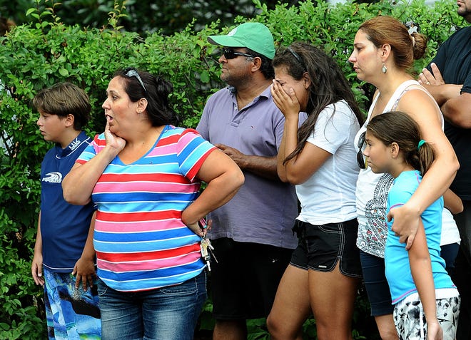 Residents of 27 Fay Road in Framingham, including Samara Rosa, second from right, and her mother Shirley Marques, second from left, react after coming home to a fire in their home. Some of the family members were on an outing at Hopkinton State Park at the time of the fire. (Daily News Staff Photo/Ken McGagh)