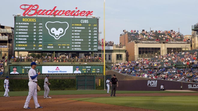 In this July 28, 2015 photo, fans at a Wrigley Rooftops' building down the right-field line outside Wrigley Field watch players during the first inning of a baseball game between the Colorado Rockies and Chicago Cubs in Chicago. A $575 million transformation started in the offseason after years of meetings, hearings and legal battles with the surrounding rooftop owners who sell unique views into the stadium. (AP Photo/Andrew A. Nelles)