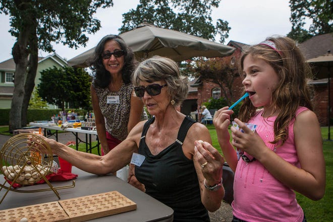 Rosalinda Case (left), Joan Loomis (middle), and Karly Nepute, 7, (right) call Bingo on Saturday at the fifth annual Springfield Block Party in the Oak Tree Neighborhood. (Mary Jane Schulte/The Register-Guard)