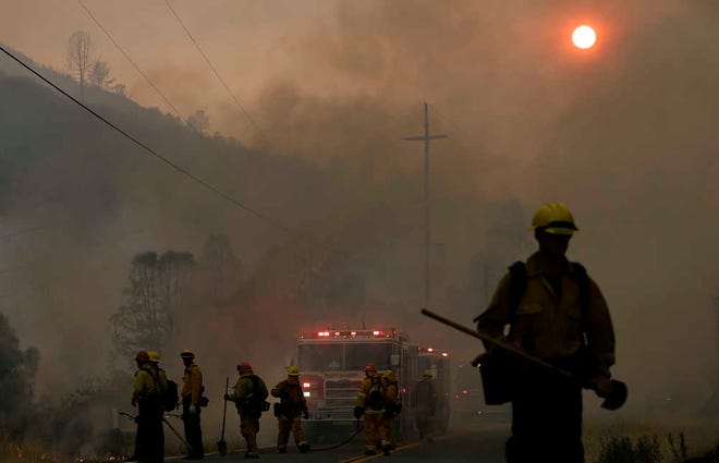Firefighters walk under smoke from fires along Morgan Valley Road near Lower Lake, Calif., Friday, July 31, 2015. A series of wildfires were intensified by dry vegetation, triple-digit temperatures and gusting winds. (AP Photo/Jeff Chiu)