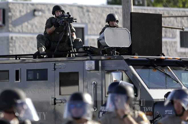 In this Aug. 9, 2014, file photo, a police tactical team moves in to disperse a group of protesters following the shooting of a young black man by a white policeman in Ferguson, Mo. Since then, legislators in almost every state have proposed changes to the way police interact with the public including measures addressing limits on the flow of surplus military equipment. AP Photo/Jeff Roberson, File