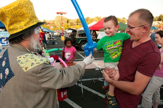 Chuckles the clown hands a blue sword to 2-yr-old Colin Little of Hatboro as his father, Bill, looks on during the Abington Police Department's Pre-Night Out event at the Abington Town Center parking lot Monday, August 3, 2015.