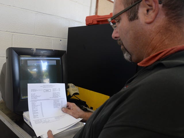 Bobby Lloyd, manager of Auto Brite on West Vernon Avenue, reads over an emissions test printout after performing an inspection Sunday.
