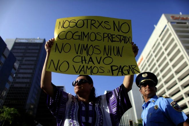A protestor holds a sign in Spanish that reads: "We didn't take out a loan. We didn't see a dime. We're not going to pay." during a protest on July 15 in San Juan demanding that the island's public debt not be paid to bondholders.
