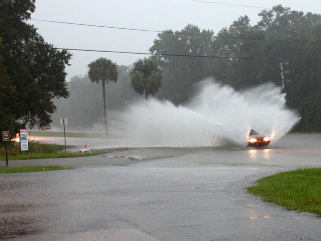 A southbound car kicks up huge plumes of water from flooding on U.S. 441 as the vehicle enters Micanopy on Monday evening.