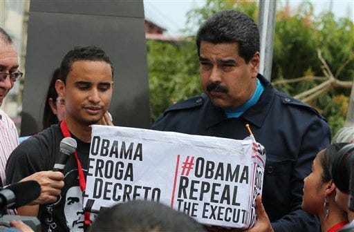 FILE - In this April 10, 2015 file photo, Venezuela's President Nicolas Maduro, right, holds a box covered by hastags that contains signatures from supporters who signed a petition asking the U.S. to end sanctions against Venezuela during a ceremony in the neighborhood of Chorrillo in Panama City. Maduro has become the third most-retweeted public figure in the world, behind Pope Francis and the King of Saudi Arabia, according to public relations firm Burston Marsteller. But a closer look suggests that the government is artificially inflating its social media pull by using networks of fake accounts. (AP Photo/Ramon Espinosa, File)