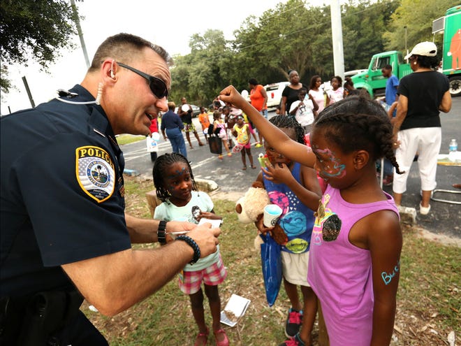 Lt. Brian Helmerson of the Gainesville Police Department hands out stickers to a group of girls during the National Night Out event held last August at Lincoln Park in Gainesville