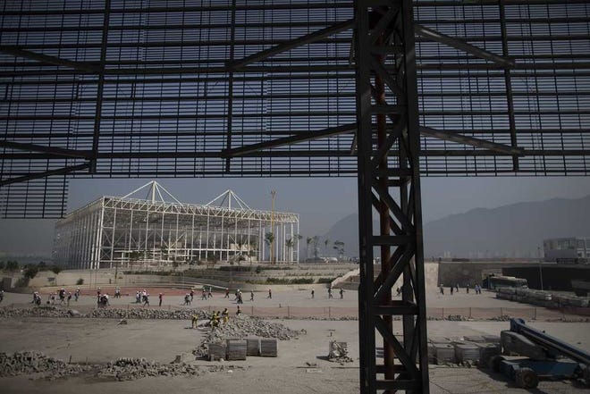 Builders work on an arena near a partially built aquatic stadium, behind, inside Olympic Park in Rio de Janeiro, Brazil, Wednesday, Aug. 5, 2015. Rio de Janeiro Mayor Eduardo Paes said on Wednesday all the venues for South America's first games are on track to be ready when the curtain comes up on Aug. 5 next year. (AP Photo/Leo Correa)