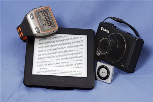 A Garmin Forerunner 310XT GPS Sports Running Multisports Speed & Distance Watch, an Amazon Kindle, Apple iPod Shuffle and a Canon S110 camera are arranged for a photo in New York, Tuesday, Aug. 4, 2015. There are times a stand-alone device works better than a jack-of-all-trades like a smartphone. (AP Photo/Richard Drew)
