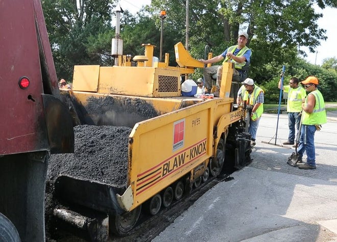 Workers lay new asphalt on Second Street, at the corner of Trent.