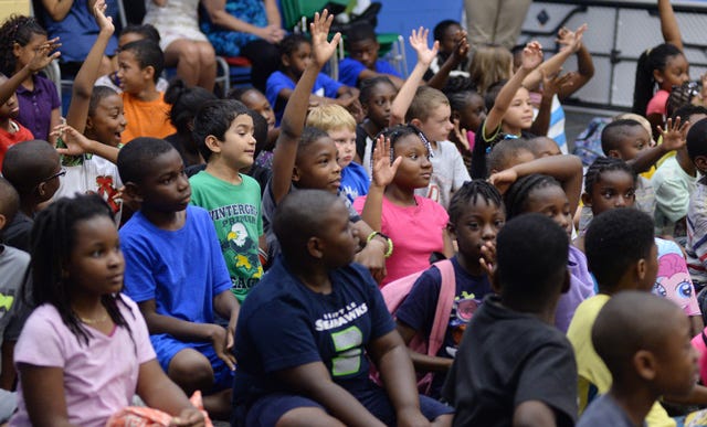 Boys and Girls Club members excitedly raise their hands at an event Wednesday at the Pitt County Boys and Girls Club in Winterville. Members were presented with back-to-school supplies provided by the Goodwill Community Foundation. A similar event will be held in Kinston next week.