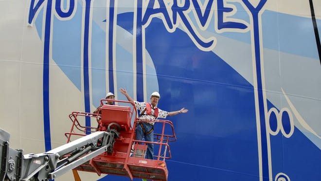 Marine wildlife artist Guy Harvey gets a close-up of the hull of Norwegian Escape, which features his artwork. The ship debuts in November in Miami. (Contributed by Norwegian Cruise Line)