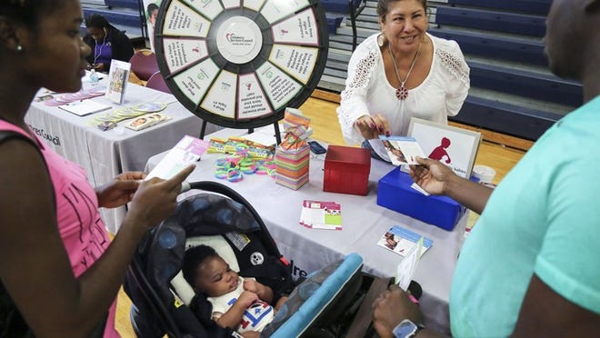 Welty O’Connor (left) and Joseph Blake (right) of Lantana attended Humana’s “Your Baby and You” event with their 2.5-month-old child Lavarie Blake at South Olive Community Center in West Palm Beach Saturday, July 25, 2015. Here, they stop at the Children’s Services Council’s Healthy Mothers, Healthy Babies booth and speak with pre-natal outreach educator Marita Alvarez (center). “We are targeting our Medicaid enrollees,” said Humana’s Medicaid Outreach Director Kurt Strohmeyer (not pictured). “The idea is to help teach them everything about their pregnancies.” (Bruce R. Bennett / The Palm Beach Post)